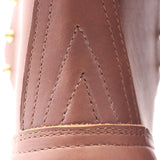 Close-up detail of a brown leather boot showing decorative stitching and a chevron pattern on the side.