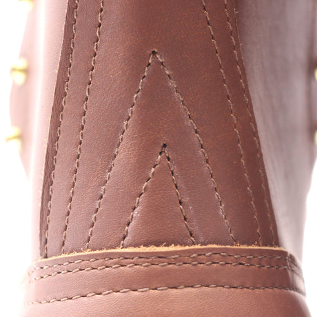 Close-up detail of a brown leather boot showing decorative stitching and a chevron pattern on the side.