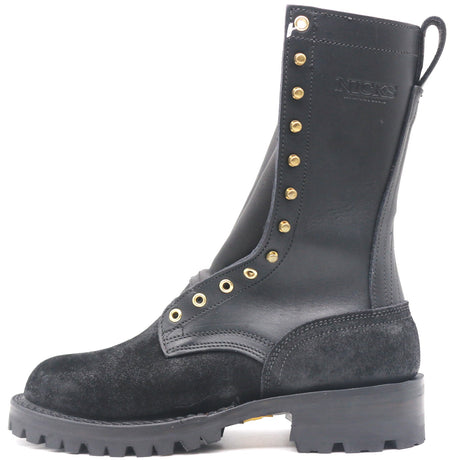 A black leather and suede lace-up work boot with gold-tone metal eyelets and studs, featuring a thick lug sole and the brand name 'NICKS' embossed on the side, shown against a plain white background.