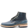A dark navy blue leather ankle boot with gold-tone metal eyelets, a stacked wood-and-leather heel, and white contrast stitching, shown from a side profile on a white background.