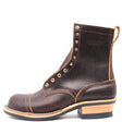 A dark brown leather lace-up ankle boot with brass eyelets, a stacked wood-look heel, and a black rubber sole, shown from a side profile on a white background.