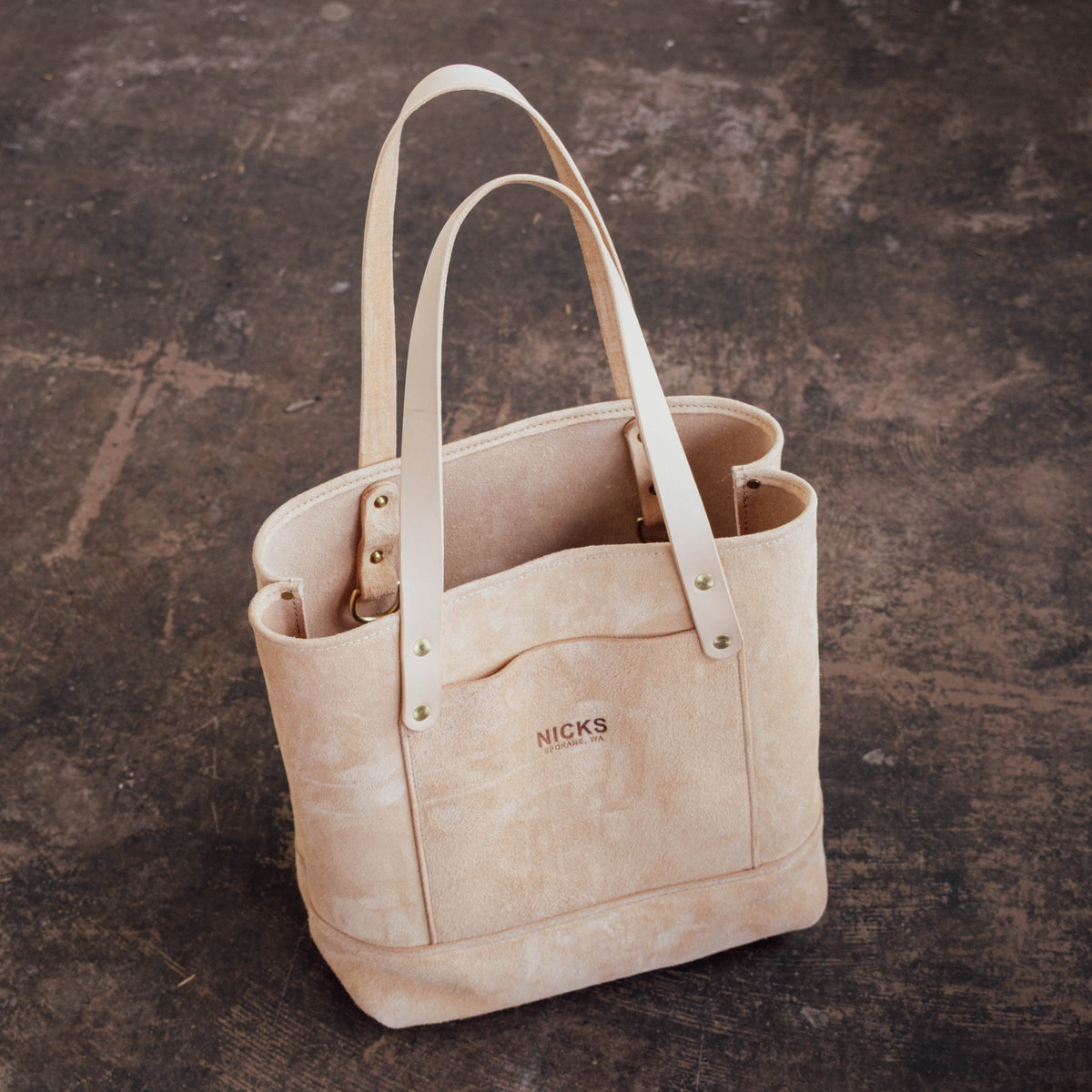 Veg Tan Suede Tote sitting on textured concrete