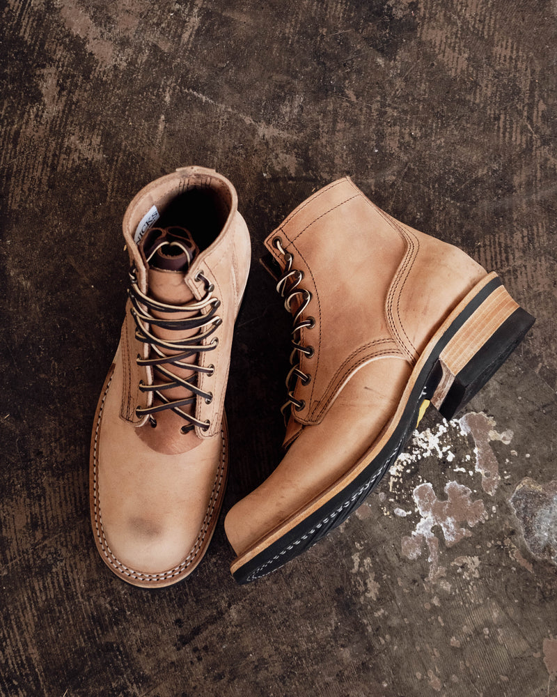 Tan leather work boots with laced fronts stacked heels and black soles shown from top and side angles