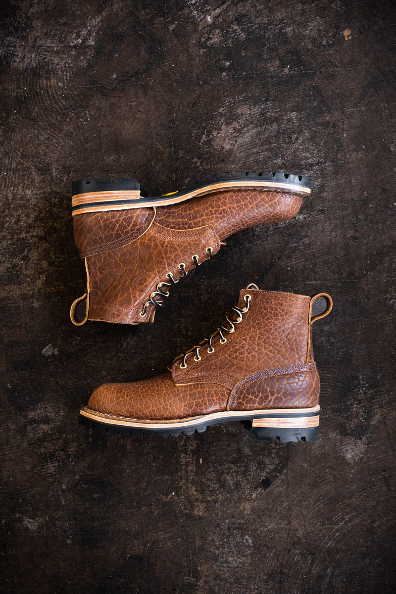 Pair of brown textured leather lace-up work boots with thick lug soles shown from the side